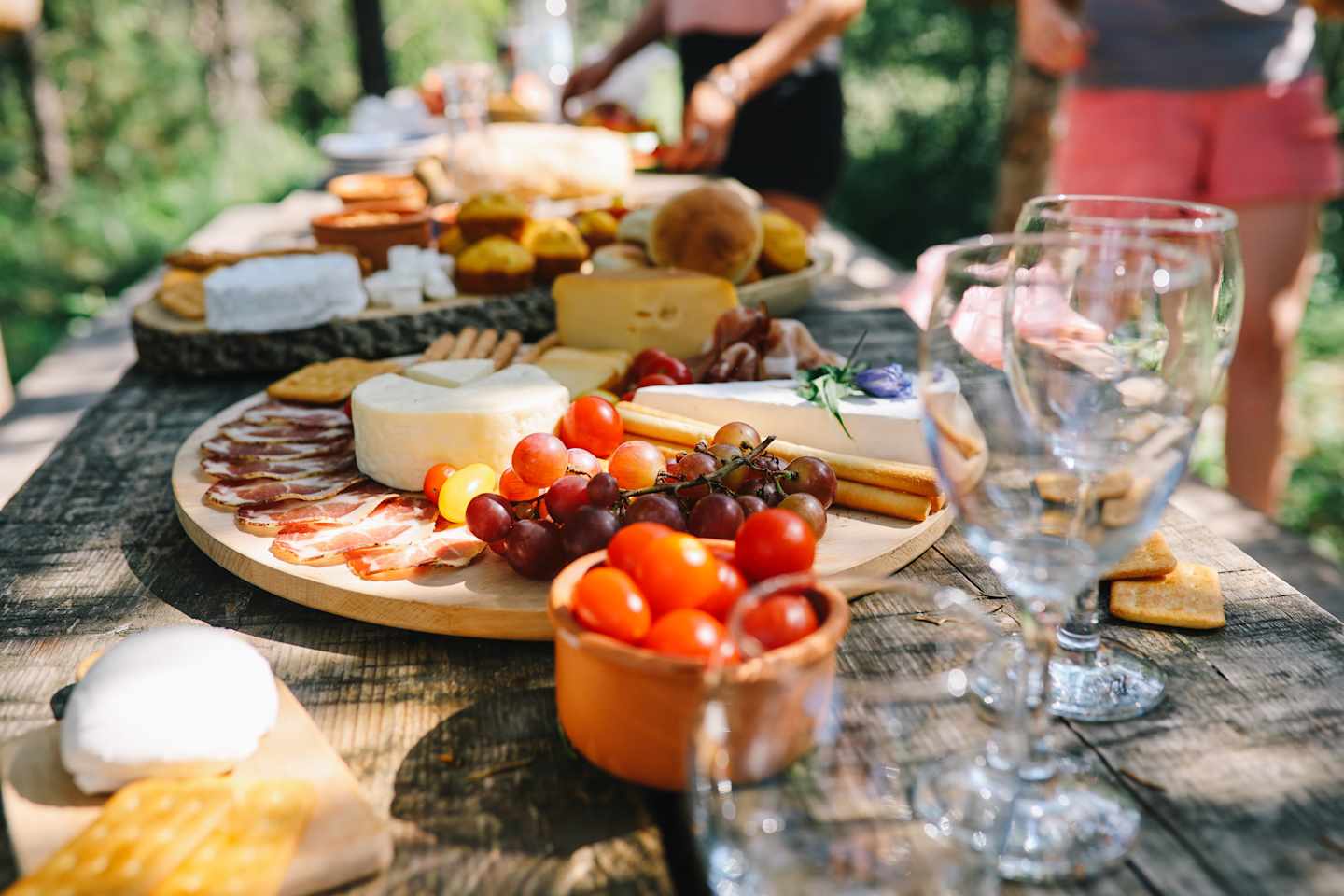 Young woman preparing various Mediterranean foods, getting ready for a picnic in the nature.
