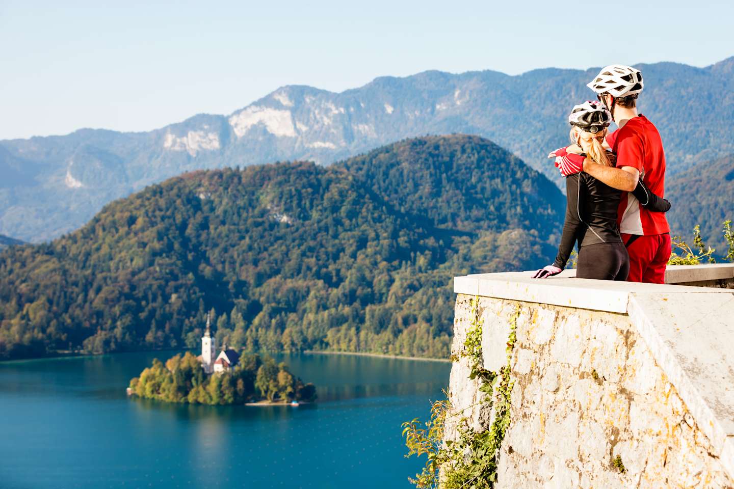Couple of mountainbikers looking at Bled lake island from Bled castle, Slovenia.
