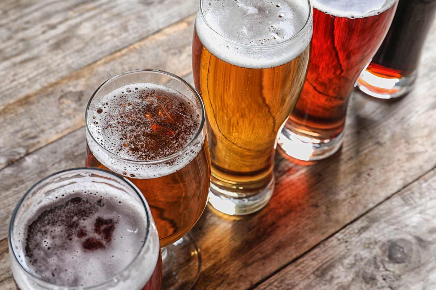 Glasses with different types of cold tasty beer on wooden table