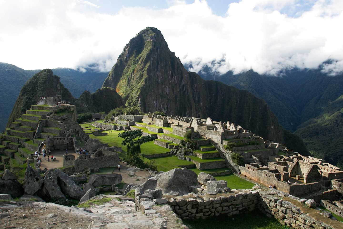 A majestic ancient Inca citadel nestled amidst towering mountains, with lush green terraces and ruins scattered across the landscape.