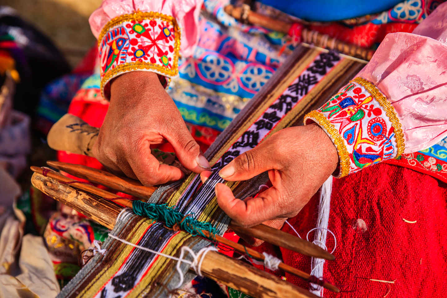 Vibrant, intricately patterned textiles and hands skillfully weaving them, showcasing the rich cultural heritage and craftsmanship.