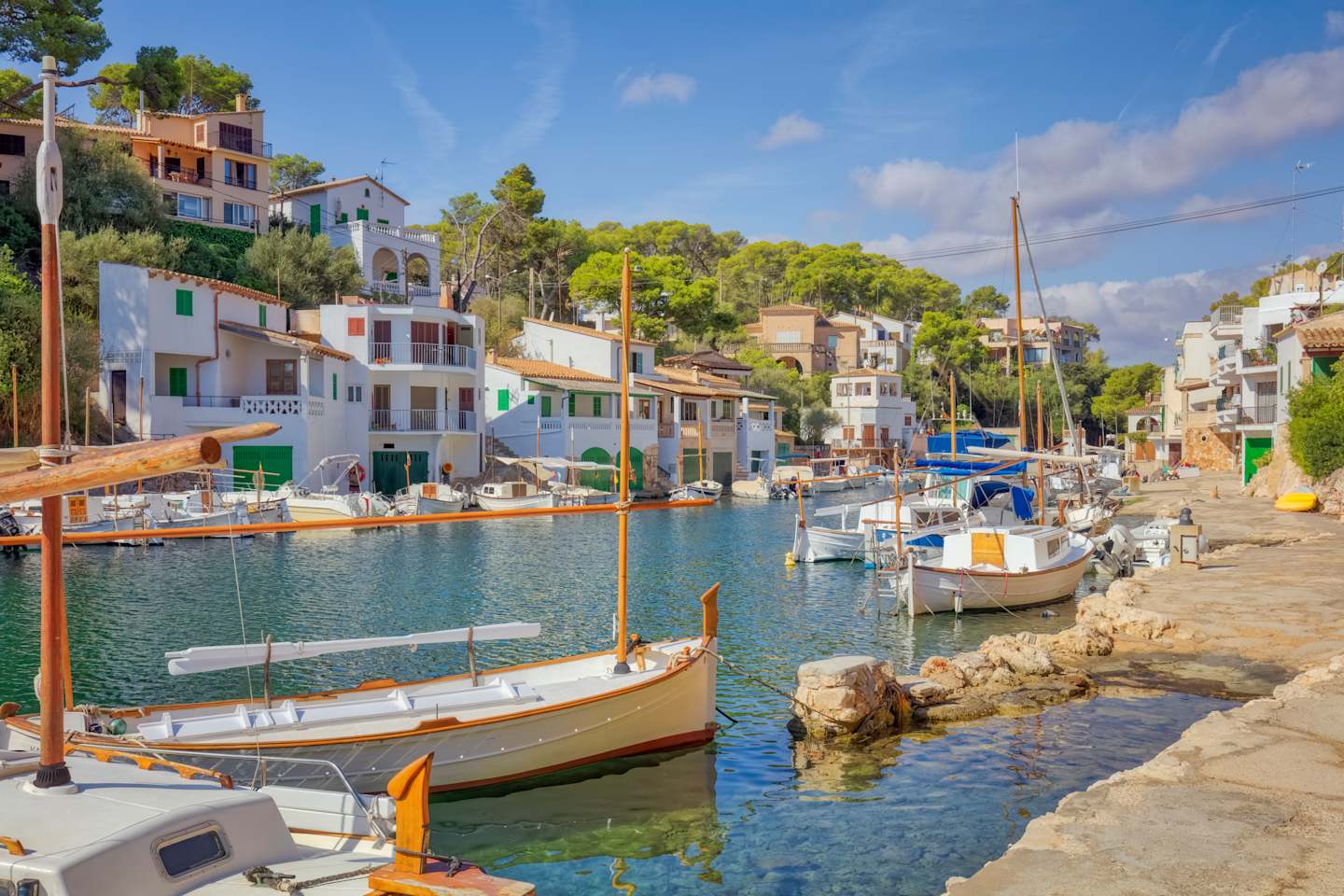 A picturesque harbor with colorful buildings, boats, and a serene waterway surrounded by lush greenery in the background.