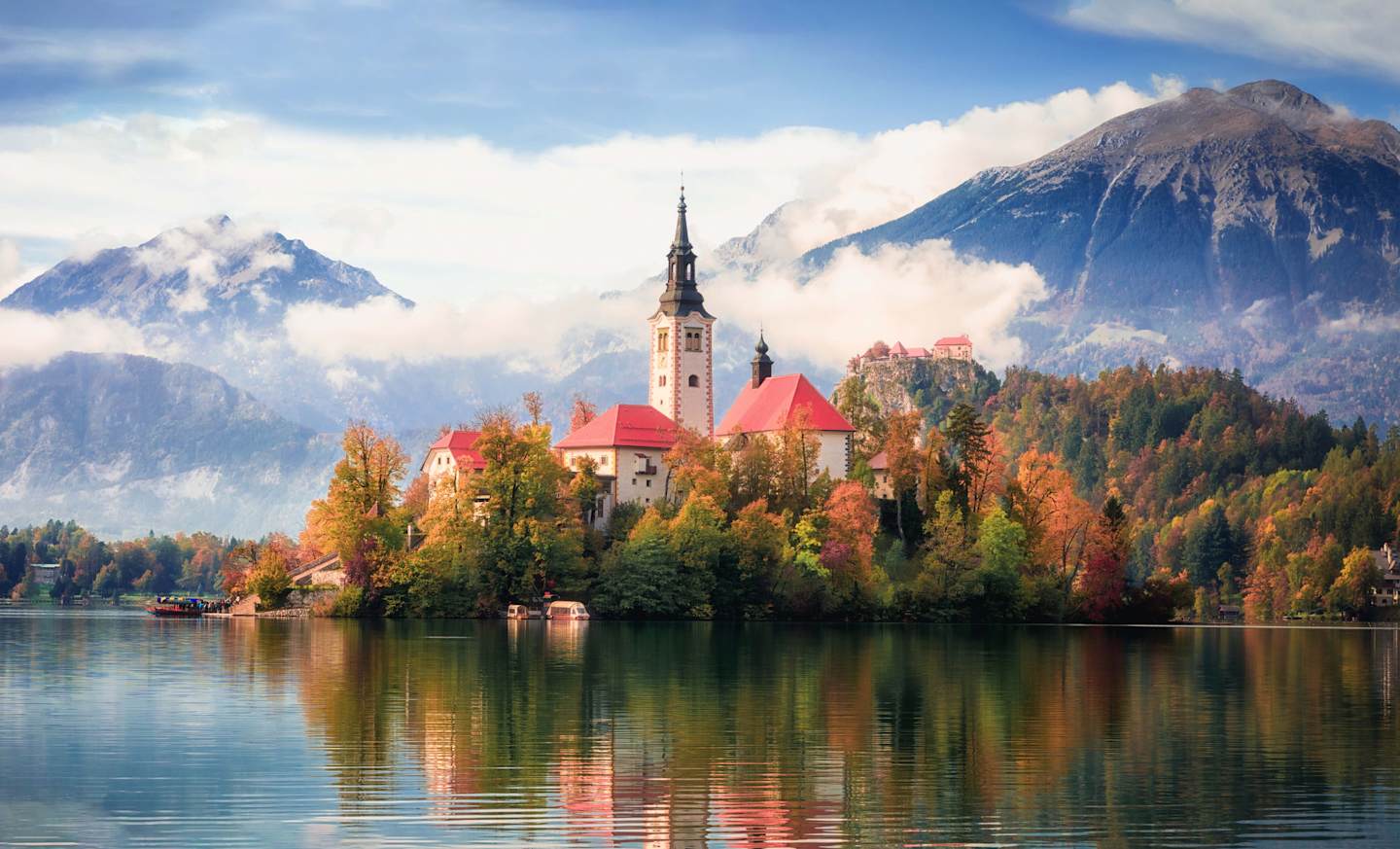 Famous alpine Bled lake in Slovenia, amazing autumn landscape. Scenic view of the lake, island with church, Bled castle, mountains and blue sky with clouds, outdoor travel background