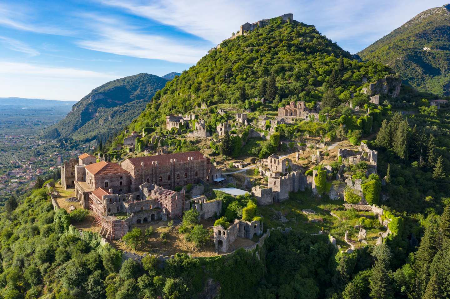 A picturesque medieval town nestled in the lush, verdant mountains, with a majestic castle perched atop a towering hill, surrounded by a dense forest canopy.