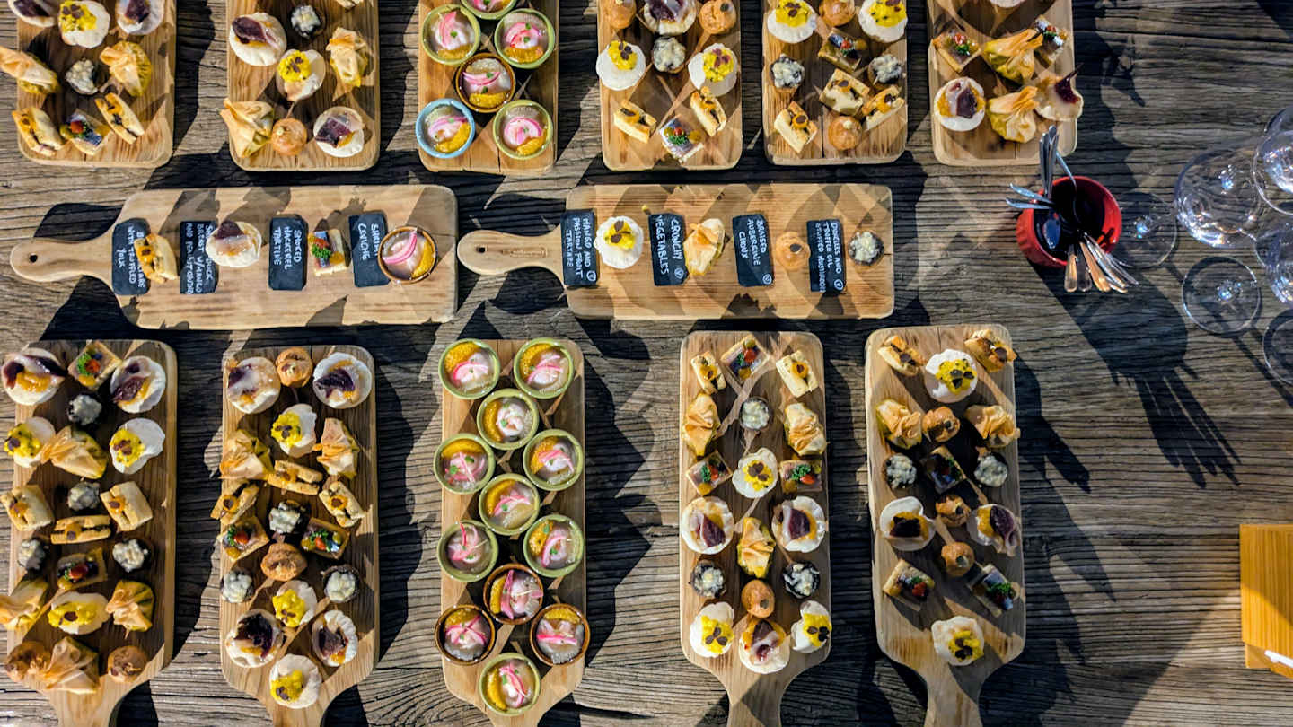 Wooden boards display an assortment of colorful, freshly prepared dishes on a rustic wooden surface.
