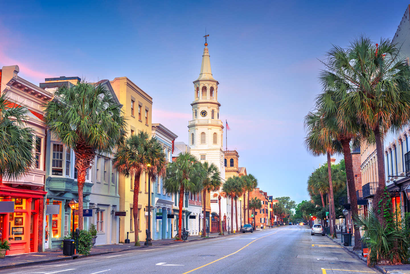 A vibrant street scene with colorful buildings, palm trees, and a tall church steeple in the background, creating a picturesque and lively atmosphere.