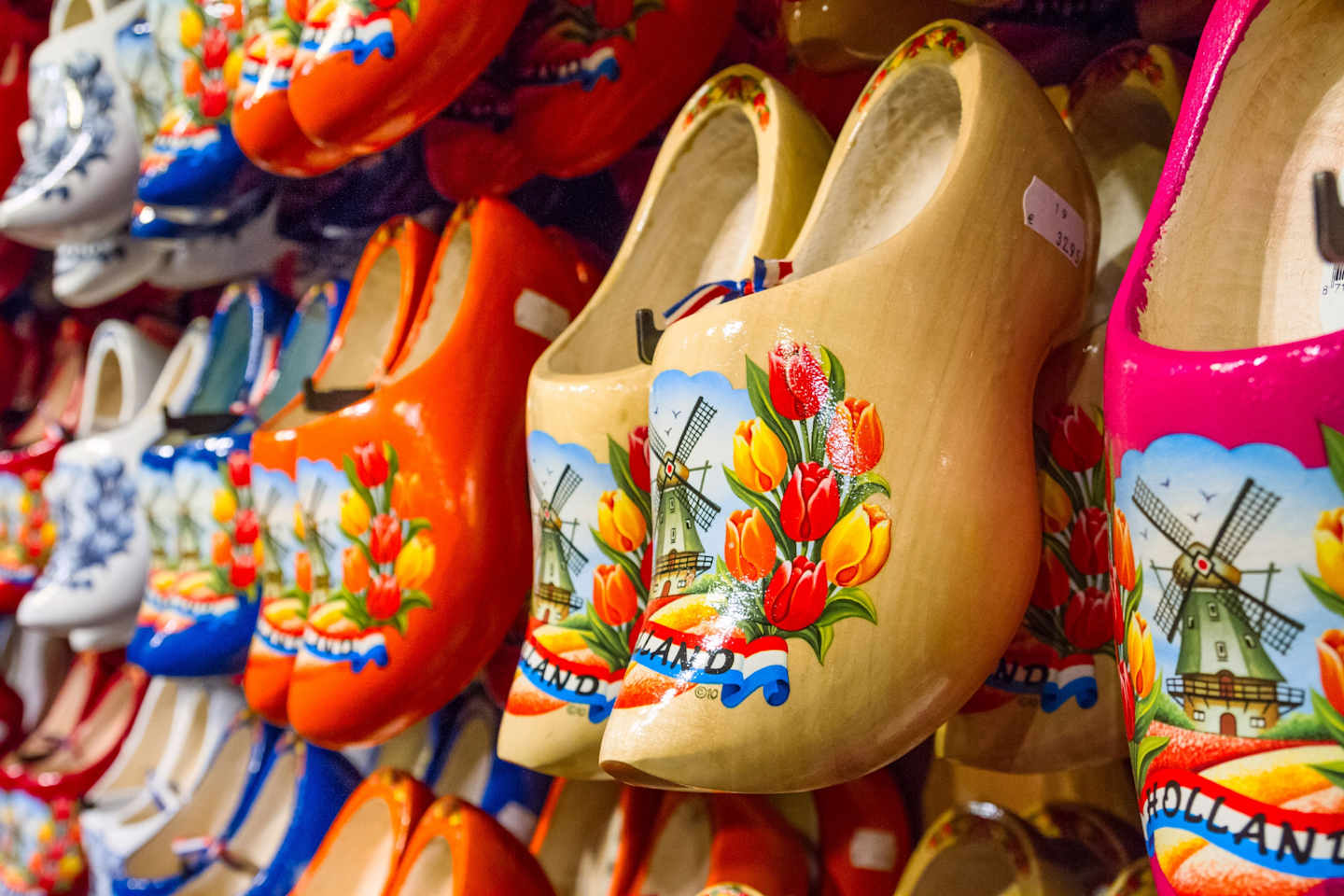 Colorful wooden clogs with vibrant floral patterns and windmill designs, displayed in a shop or market setting.