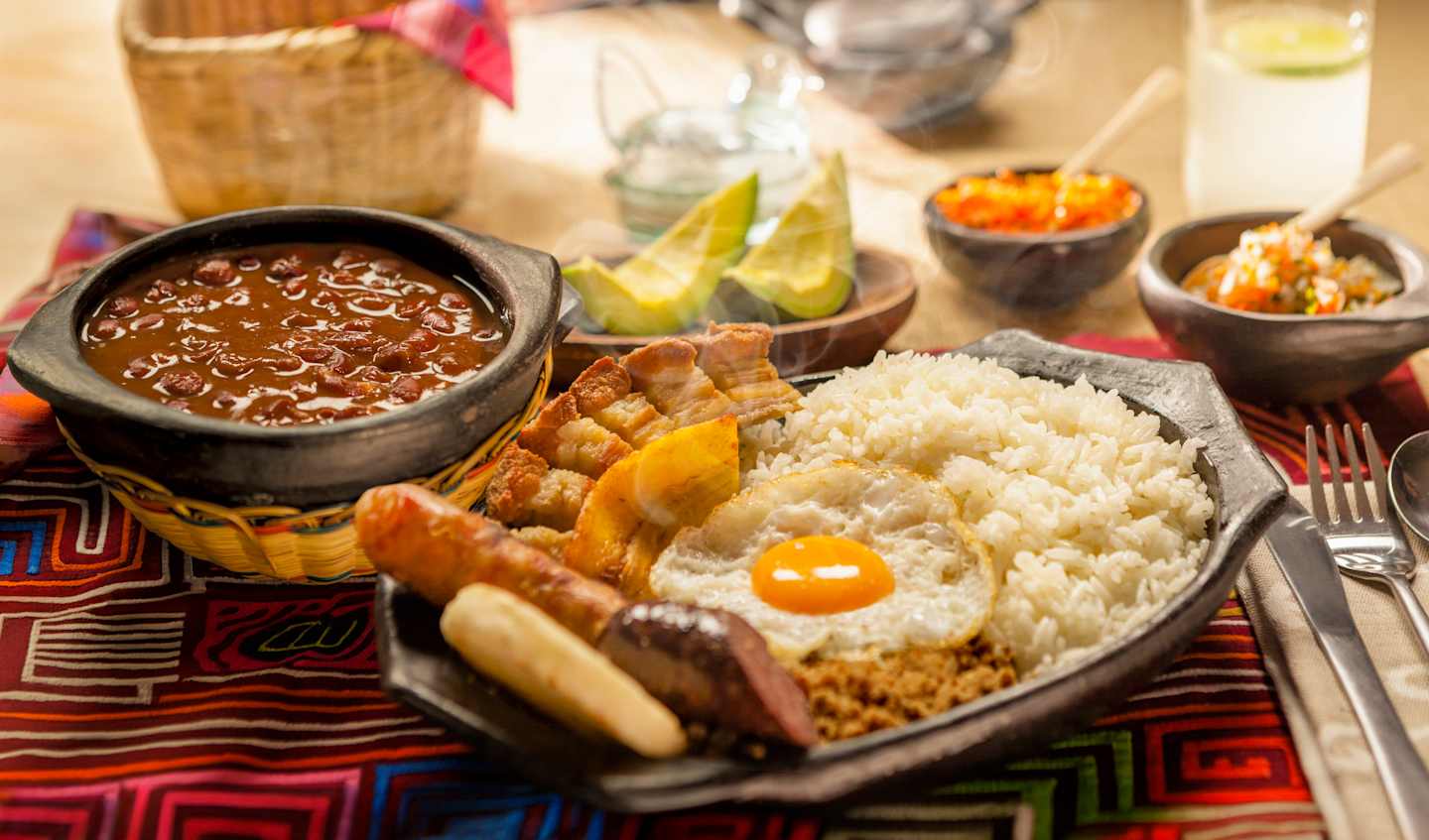 A colorful and diverse array of traditional Mexican dishes, including rice, beans, sauces, and various accompaniments, arranged on a patterned cloth.