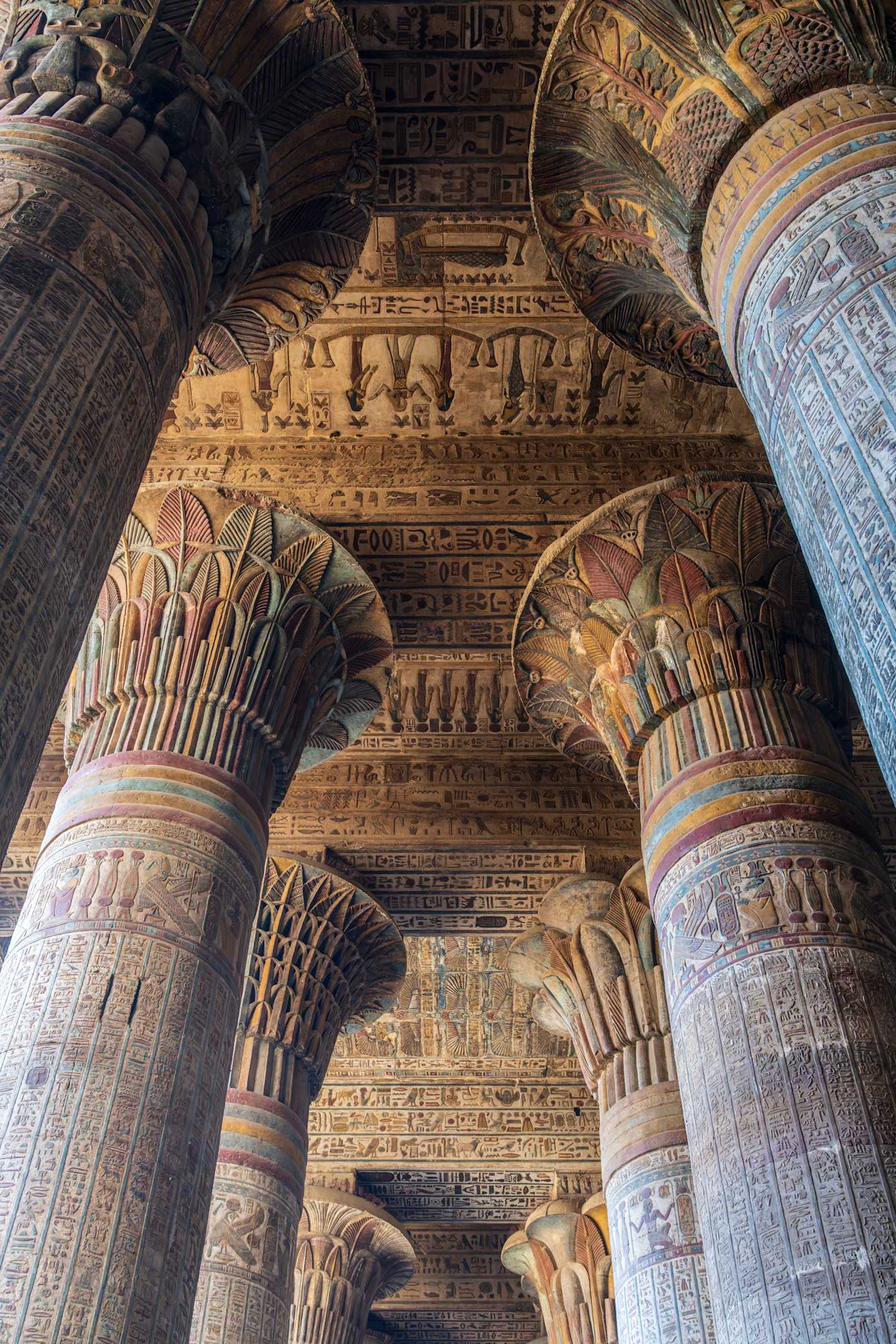 Ornate and intricately decorated columns with intricate carvings and patterns dominate the foreground, while the background features a complex, layered architectural structure with additional decorative elements.