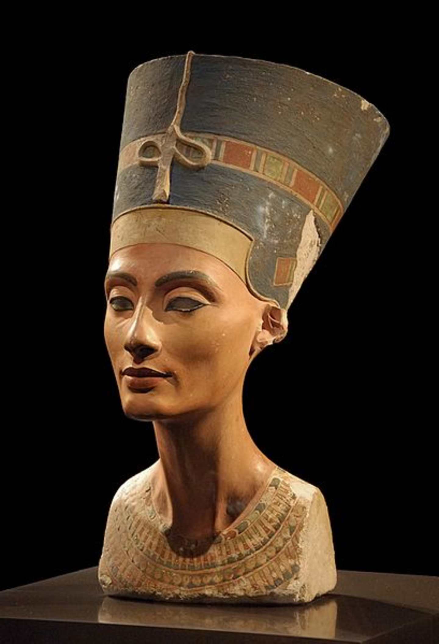A detailed bust sculpture of an ancient Egyptian queen or goddess, featuring an ornate headdress and intricate facial features, set against a dark background.