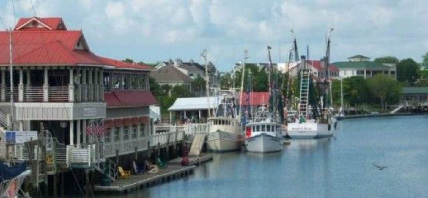 A harbor with various boats and ships docked, surrounded by colorful buildings and structures in the background.