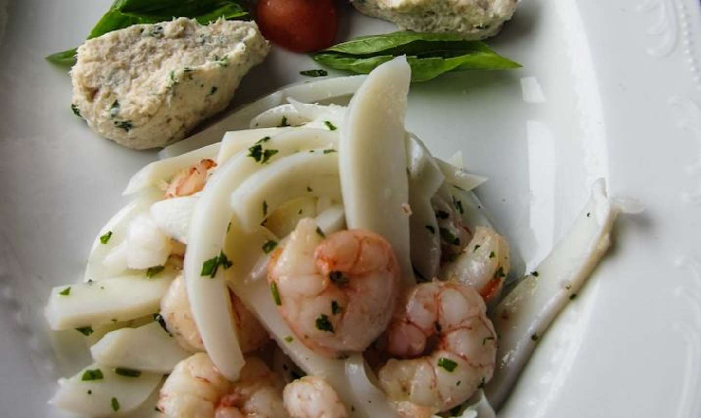 The image shows a plate with various food items, including what appears to be a salad or slaw with shredded vegetables and shrimp, as well as some bread-like items on the side.