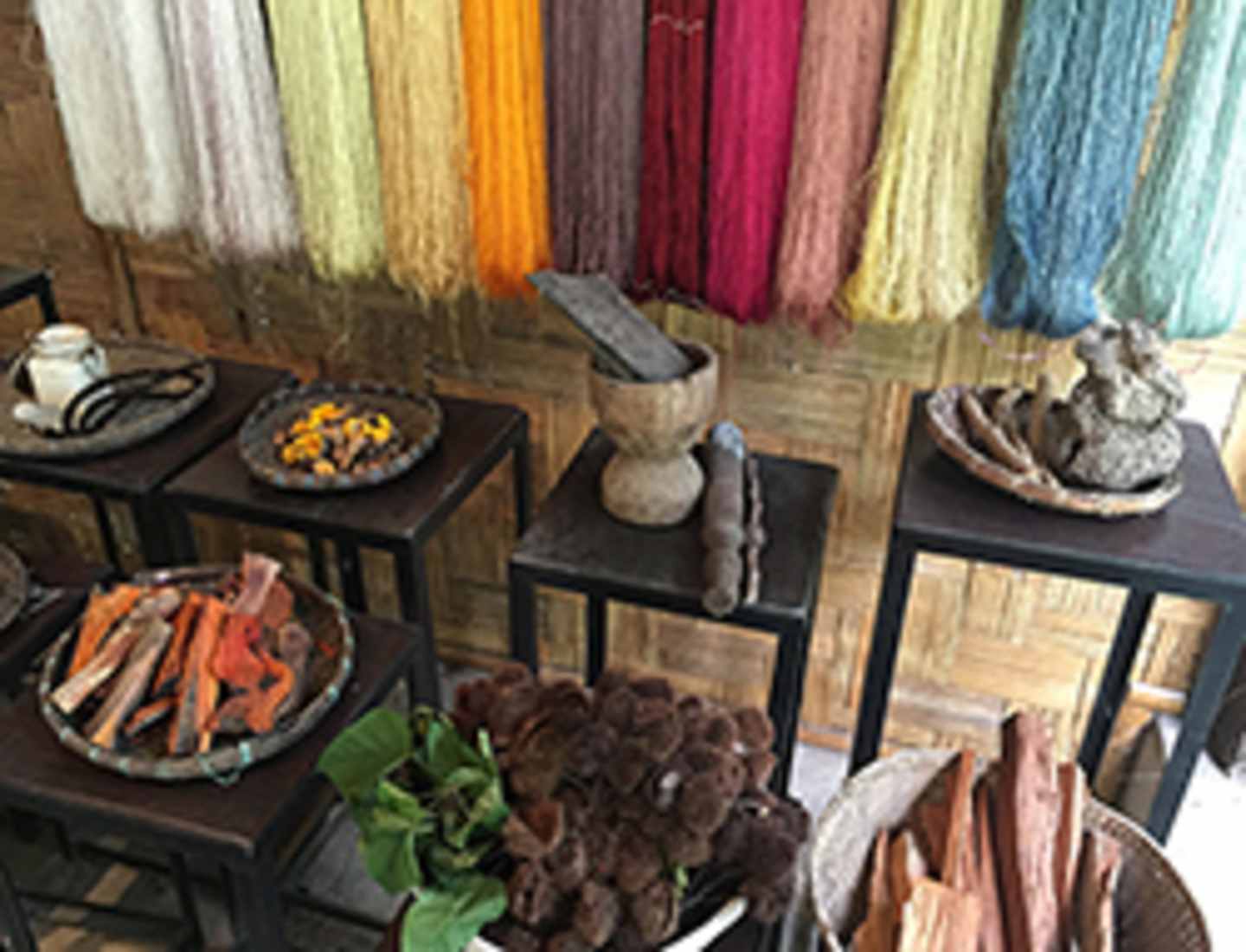 The image depicts a display of various colorful yarns, dried flowers, and other decorative items arranged on wooden shelves and tables.