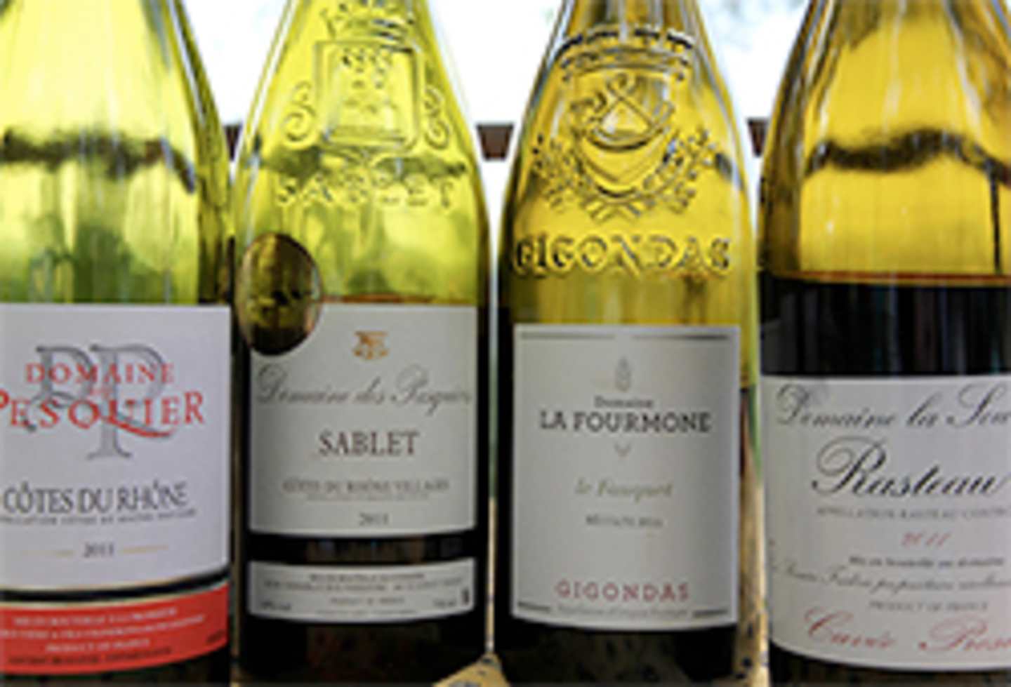 The image shows several bottles of wine, with various labels and designs, arranged in the foreground against a blurred background.