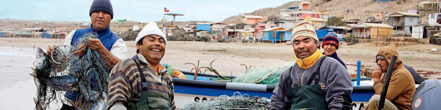 Two men in traditional clothing stand in the foreground, surrounded by a colorful, mountainous village in the background.