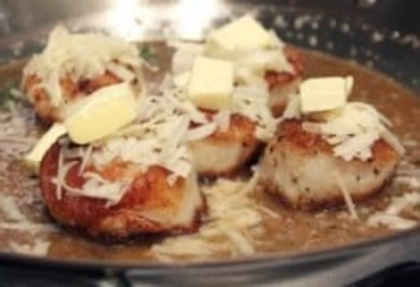 A plate filled with baked potatoes topped with melted cheese, sour cream, and chives, set against a dark background.