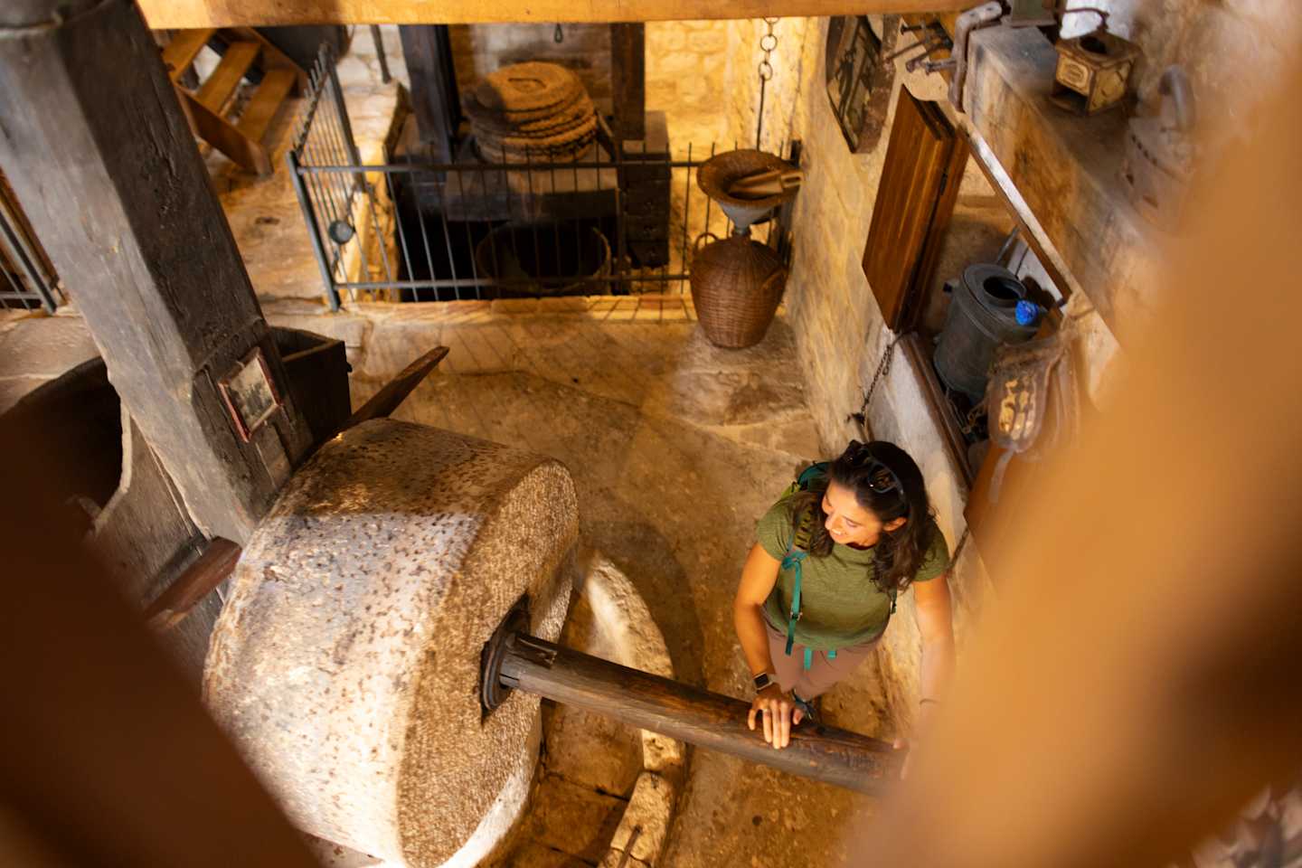 A woman stands in a cluttered, rustic-looking room filled with various objects and furniture.