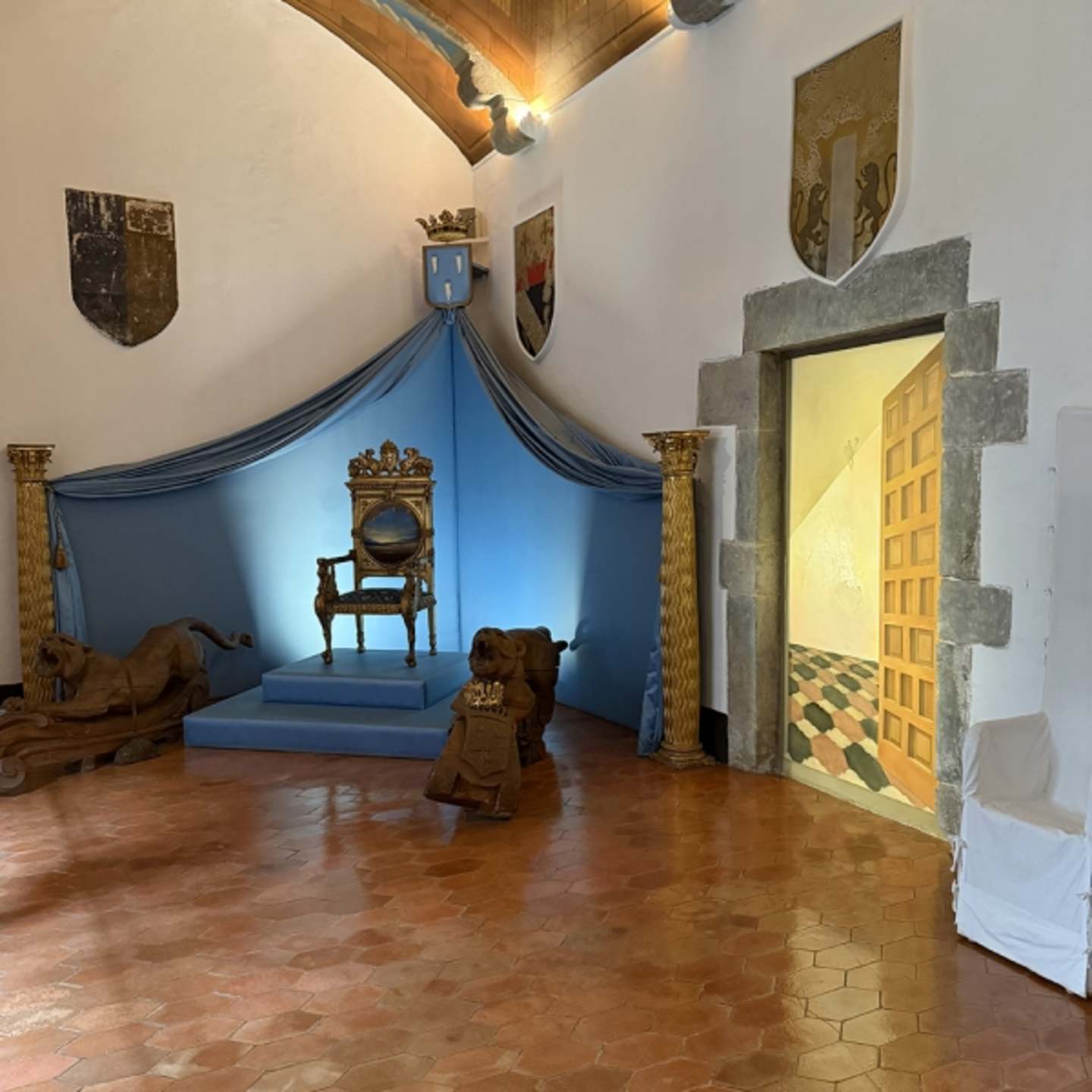 A grand, ornate bedroom with a canopy bed, antique furniture, and decorative elements like shields and coats of arms adorning the walls, creating an atmosphere of historical grandeur.