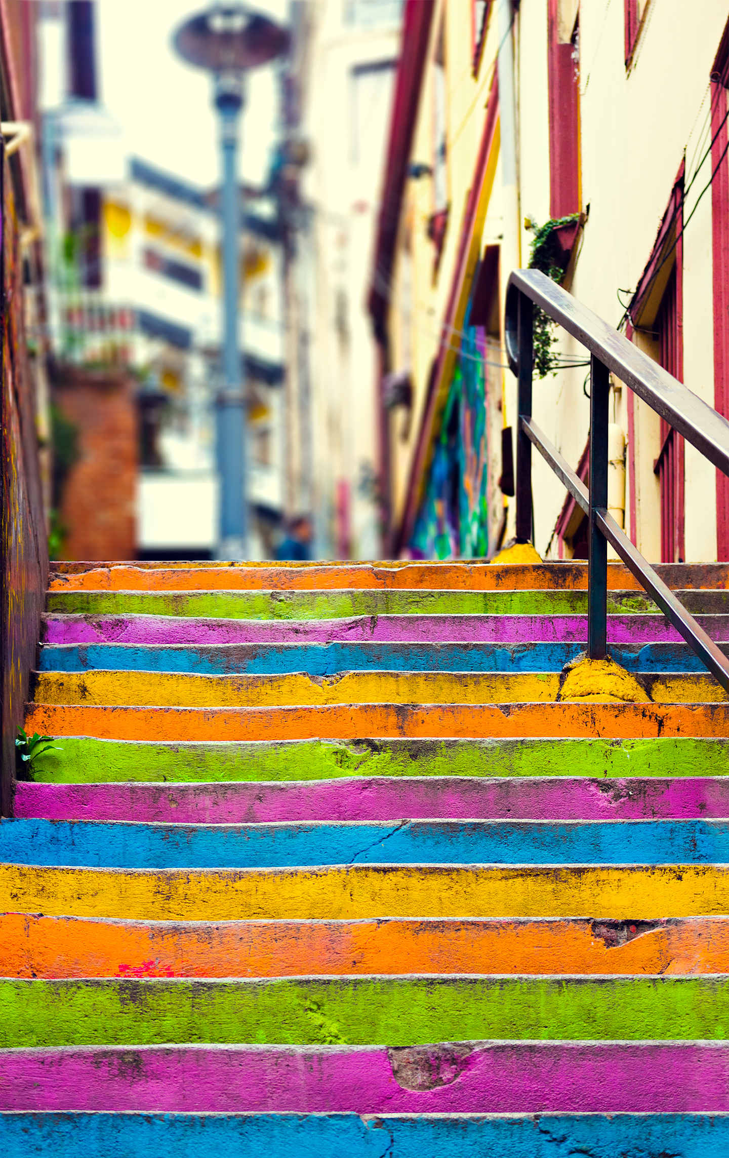Vibrant, multicolored wooden stairs lead up to a building, with various objects and structures visible in the background.