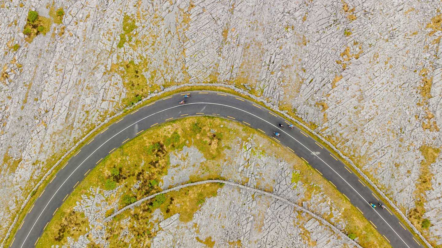 A winding road carved through a textured, moss-covered surface, creating a striking contrast between the natural and artificial elements.