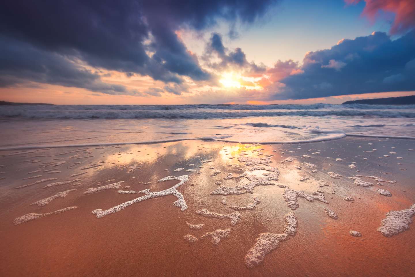 A serene beach scene with a dramatic sky, the sun's rays peeking through the clouds and reflecting on the wet sand, creating a captivating and tranquil atmosphere.