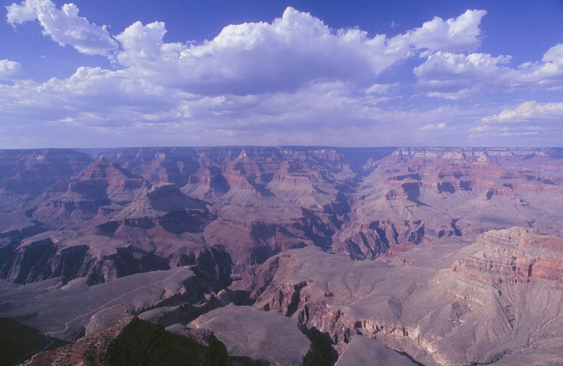 A vast and majestic Grand Canyon landscape stretches out beneath a dramatic, cloud-filled sky.