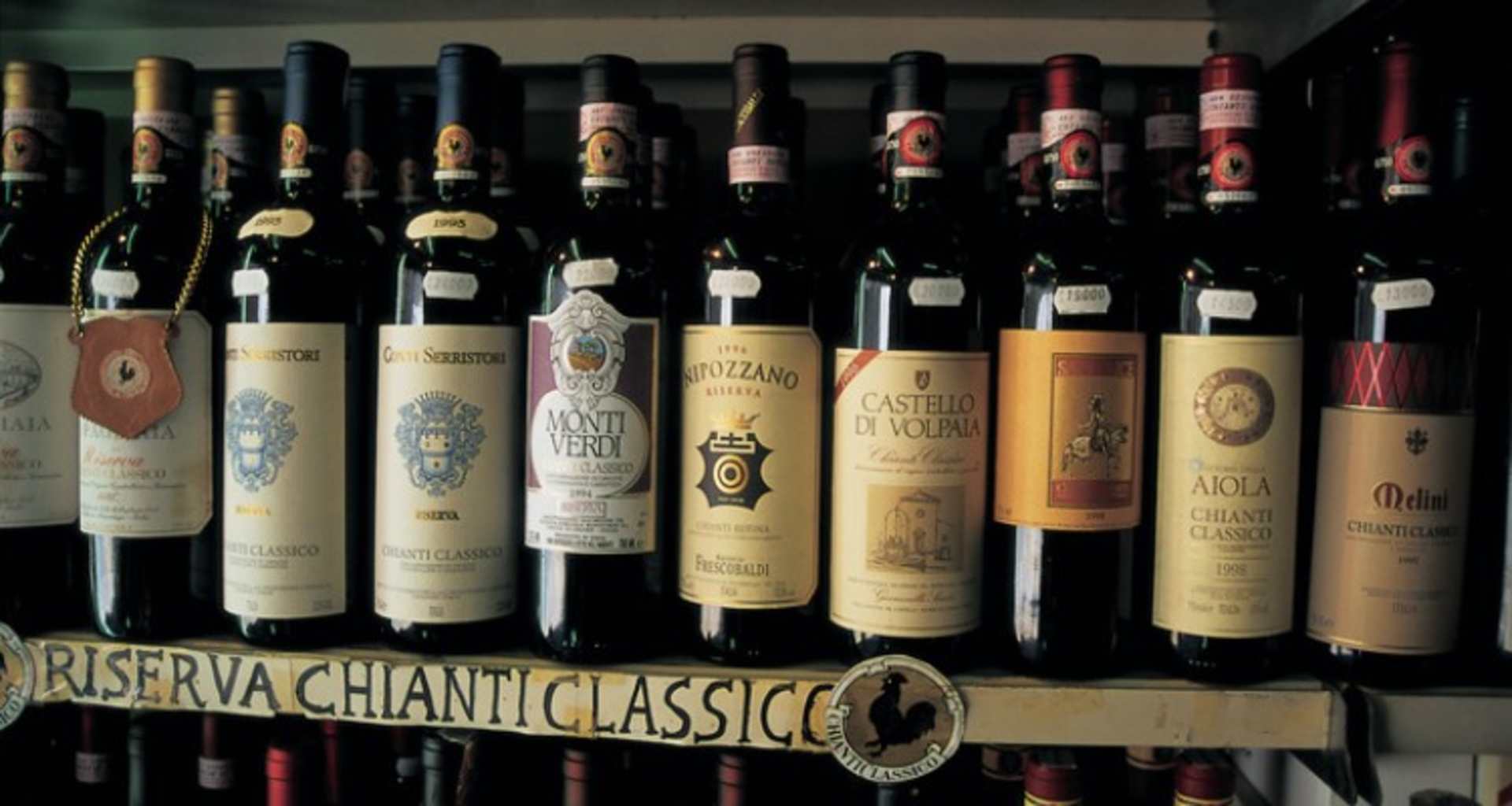 A collection of various bottles of Chianti Classico wine displayed on a shelf, with the "Riserva Chianti Classico" label prominently featured in the foreground.