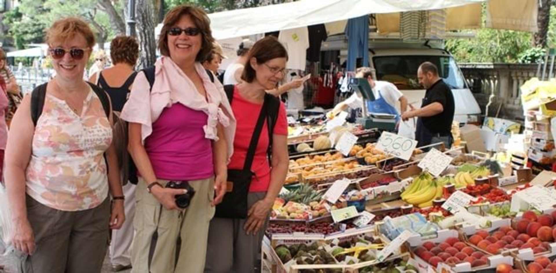 A group of women browsing through a vibrant outdoor market, surrounded by an array of colorful produce and goods displayed on stalls.