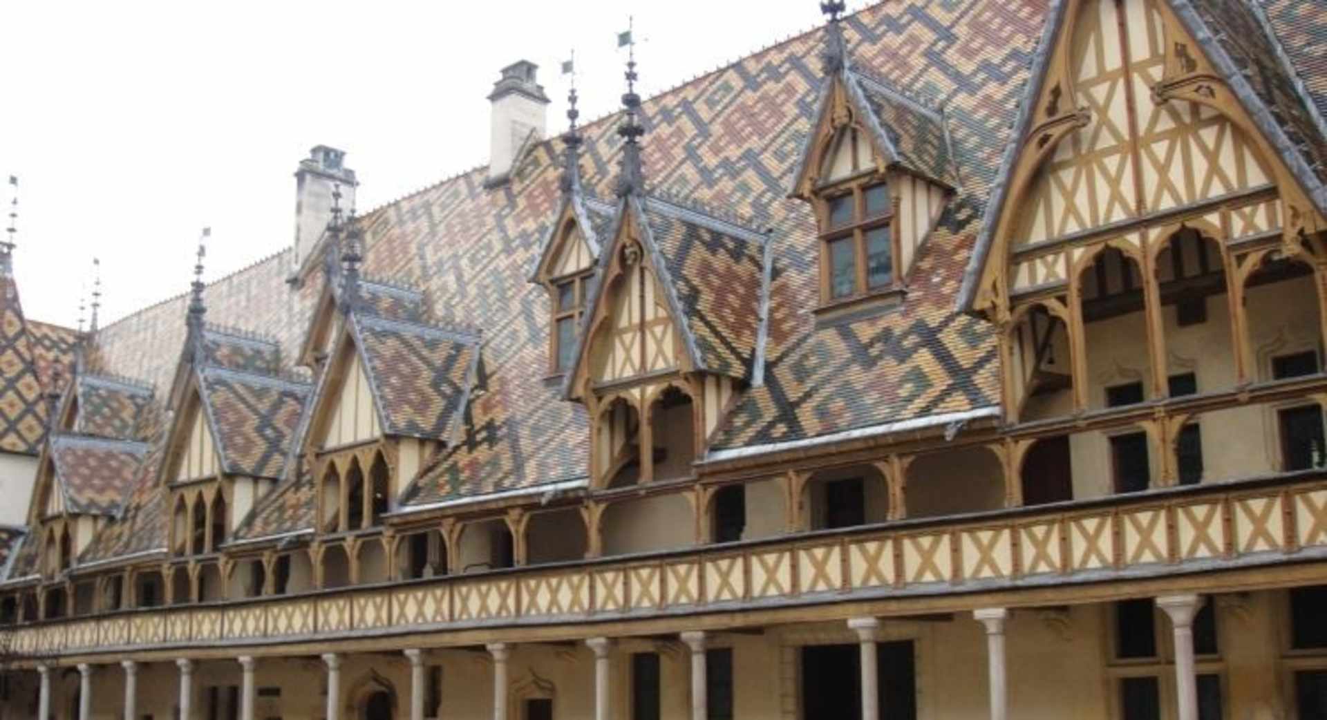 A historic, multi-story building with intricate brick and timber-framed architecture, featuring ornate roofs and windows, stands prominently in the foreground.