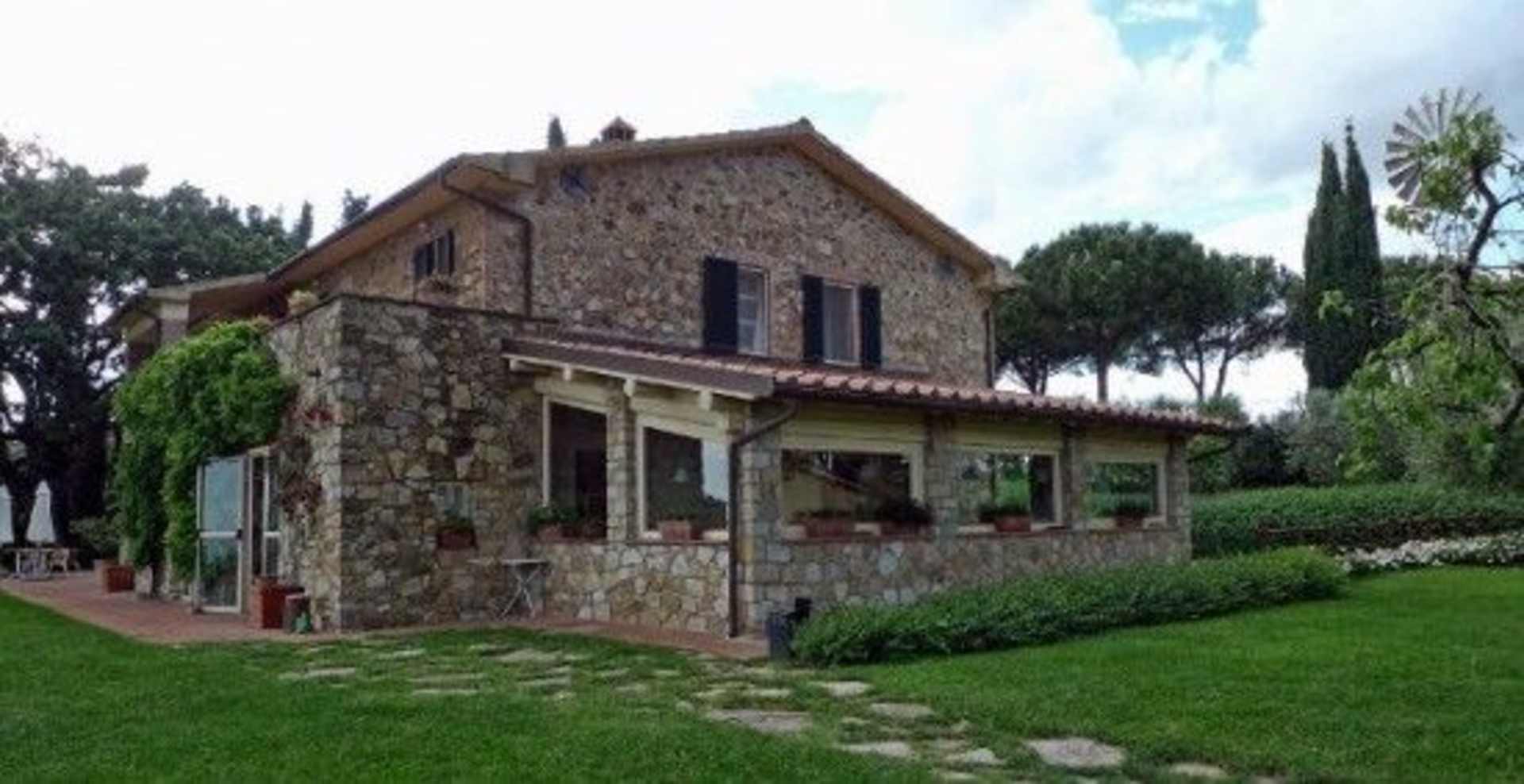 A charming stone cottage nestled in a lush, verdant landscape, with a cobblestone path leading to the entrance and surrounded by towering trees and shrubs.