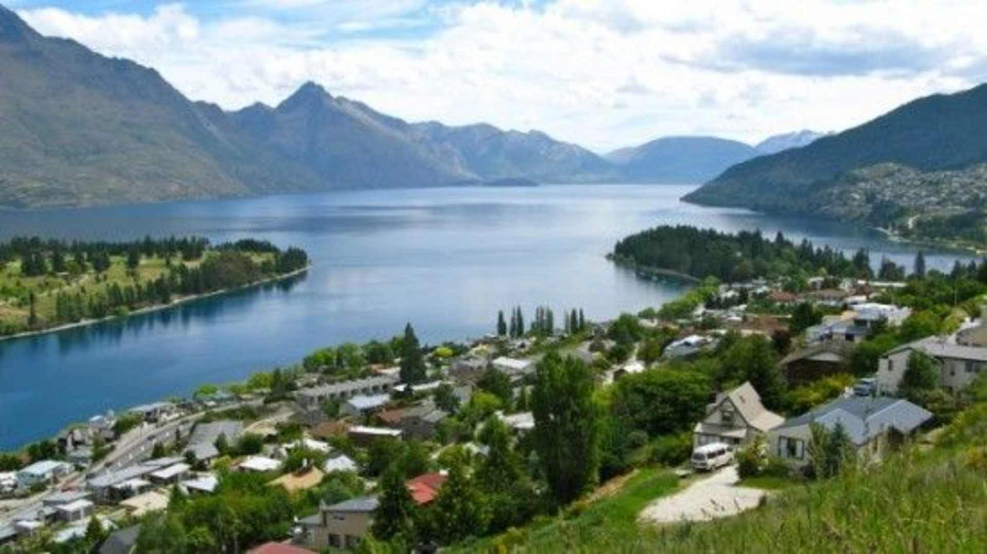 A picturesque alpine town nestled along the shores of a serene, turquoise lake, surrounded by majestic, snow-capped mountains in the distance.