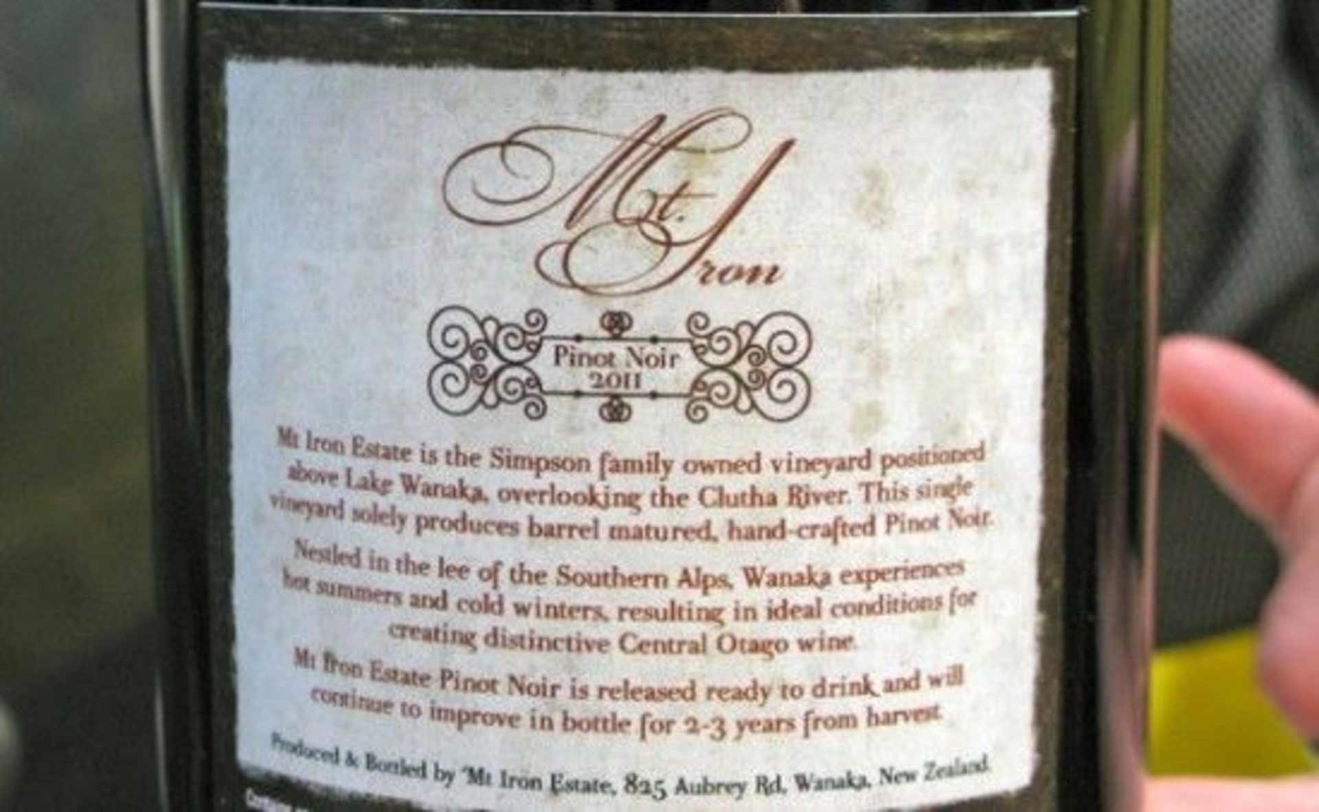 The image shows a bottle of Mt. Iron Pinot Noir wine, with a label that provides information about the wine's origin and production details.