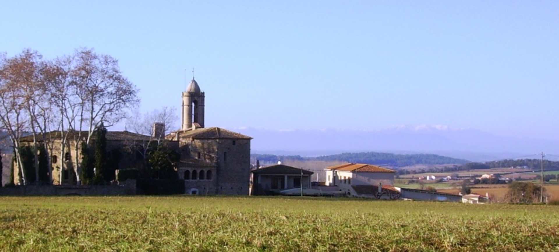 A picturesque village nestled in a lush, rolling landscape, with a tall church steeple rising above the charming buildings in the foreground.