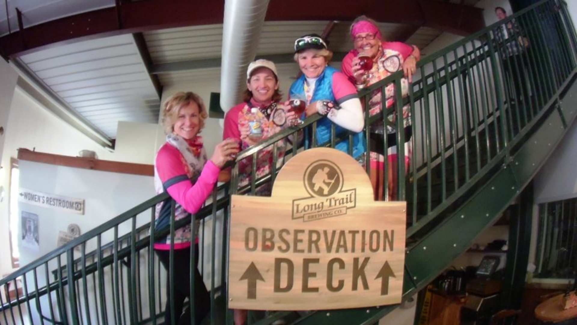 A group of people, dressed in colorful outfits, are standing on an observation deck with a sign indicating the location.