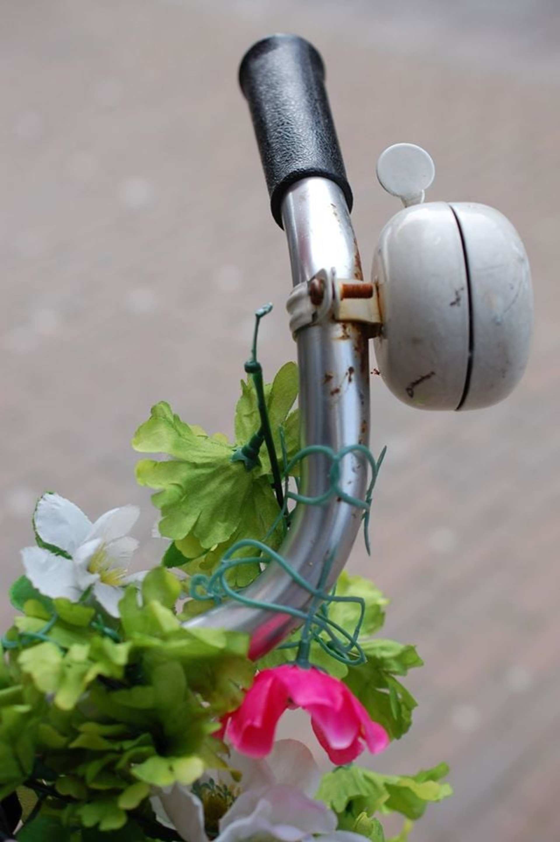 A close-up view of a robotic arm holding a variety of fresh green leaves and a vibrant pink flower against a blurred background.