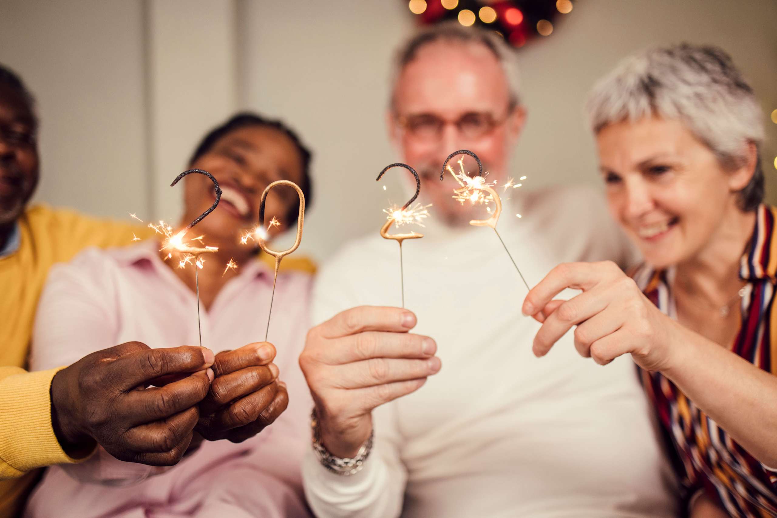 A group of people holding sparklers and celebrating together in a festive setting with colorful lights in the background.