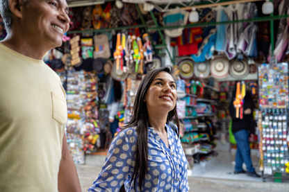 Two people, a man and a woman, are standing in a colorful and cluttered store filled with various merchandise and decorations.