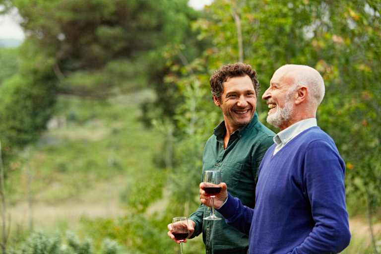 Cheerful father and son having red wine while walking in park
