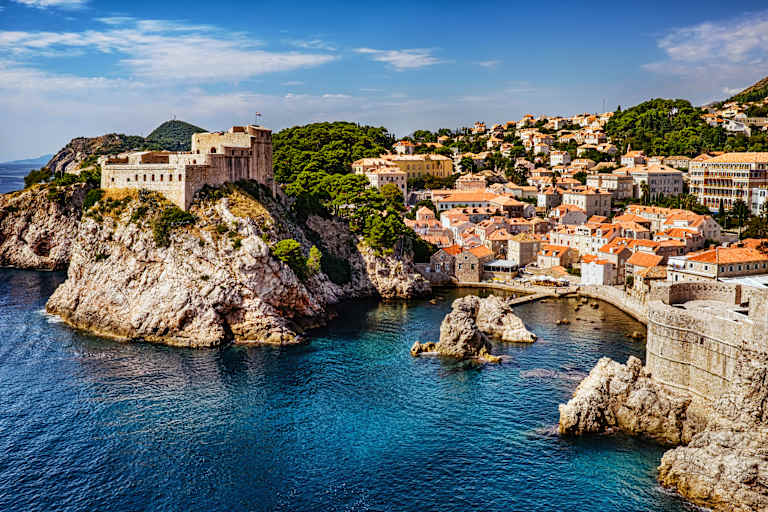 A picturesque coastal town nestled among rocky cliffs, with colorful buildings and a serene blue sea in the foreground.