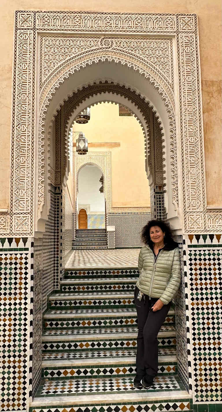 A vibrant array of colorful leather tanning vats and drying racks fills the foreground, surrounded by the traditional architecture of the historic Moroccan city in the background.