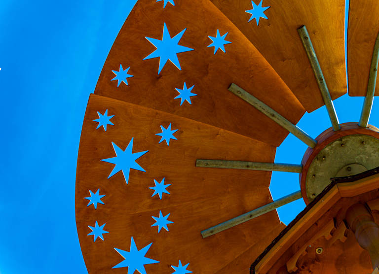 A wooden structure with star cutouts is set against a bright blue sky.