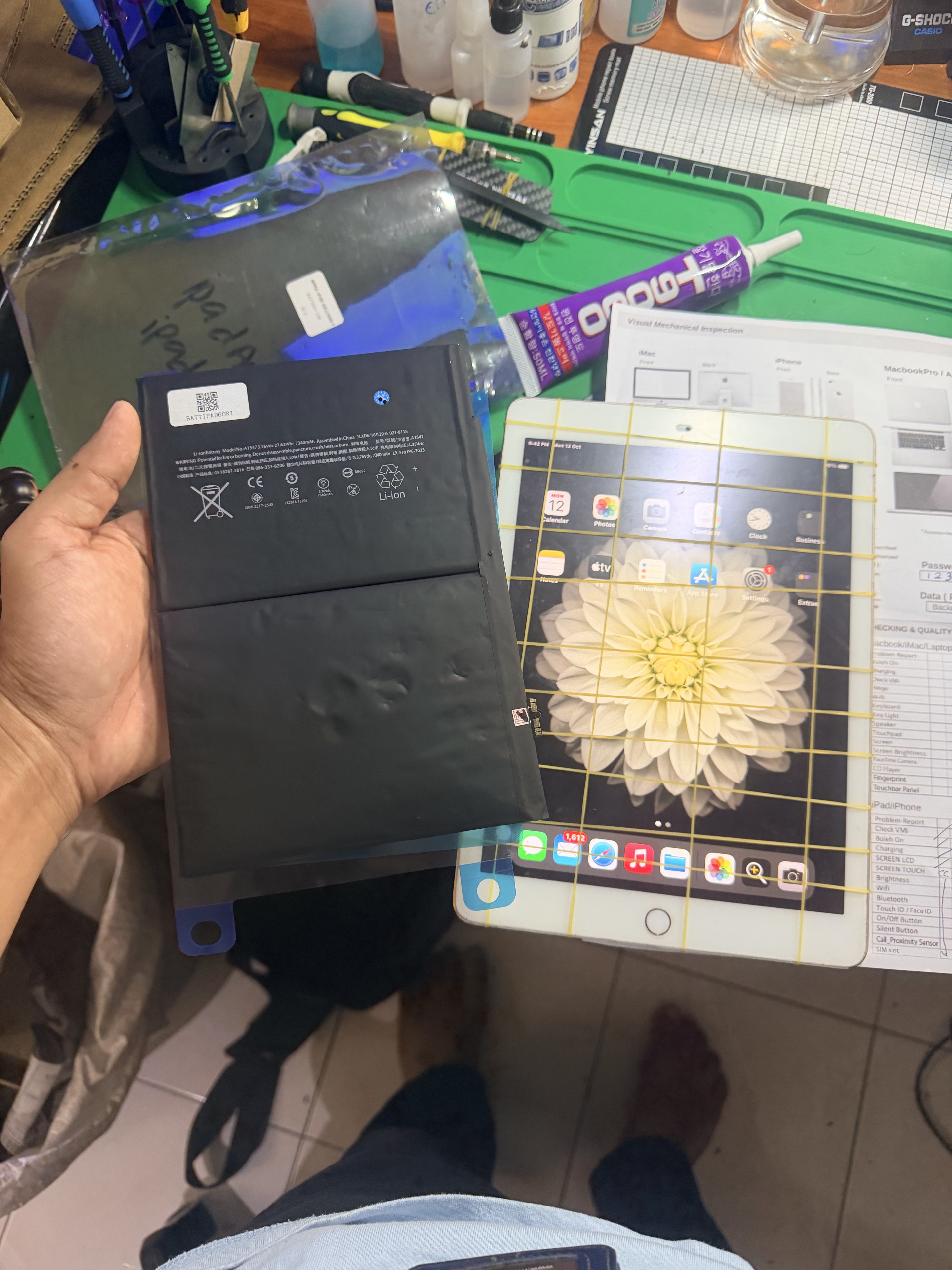 Bateri iPad dipegang bersebelahan sebuah iPad di meja kerja