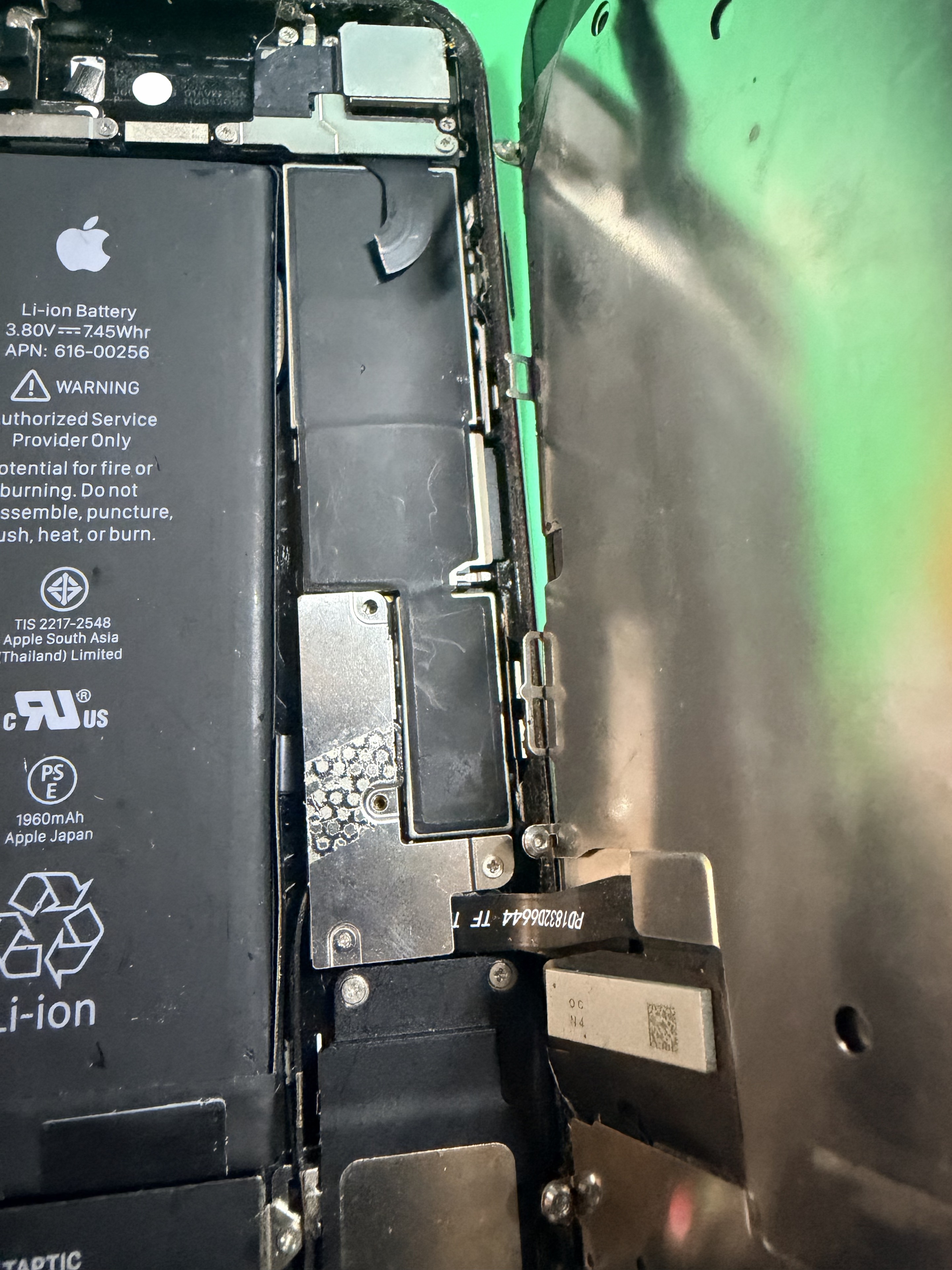 Pandangan dekat bateri dan komponen dalaman iPhone dengan skrin dibuka