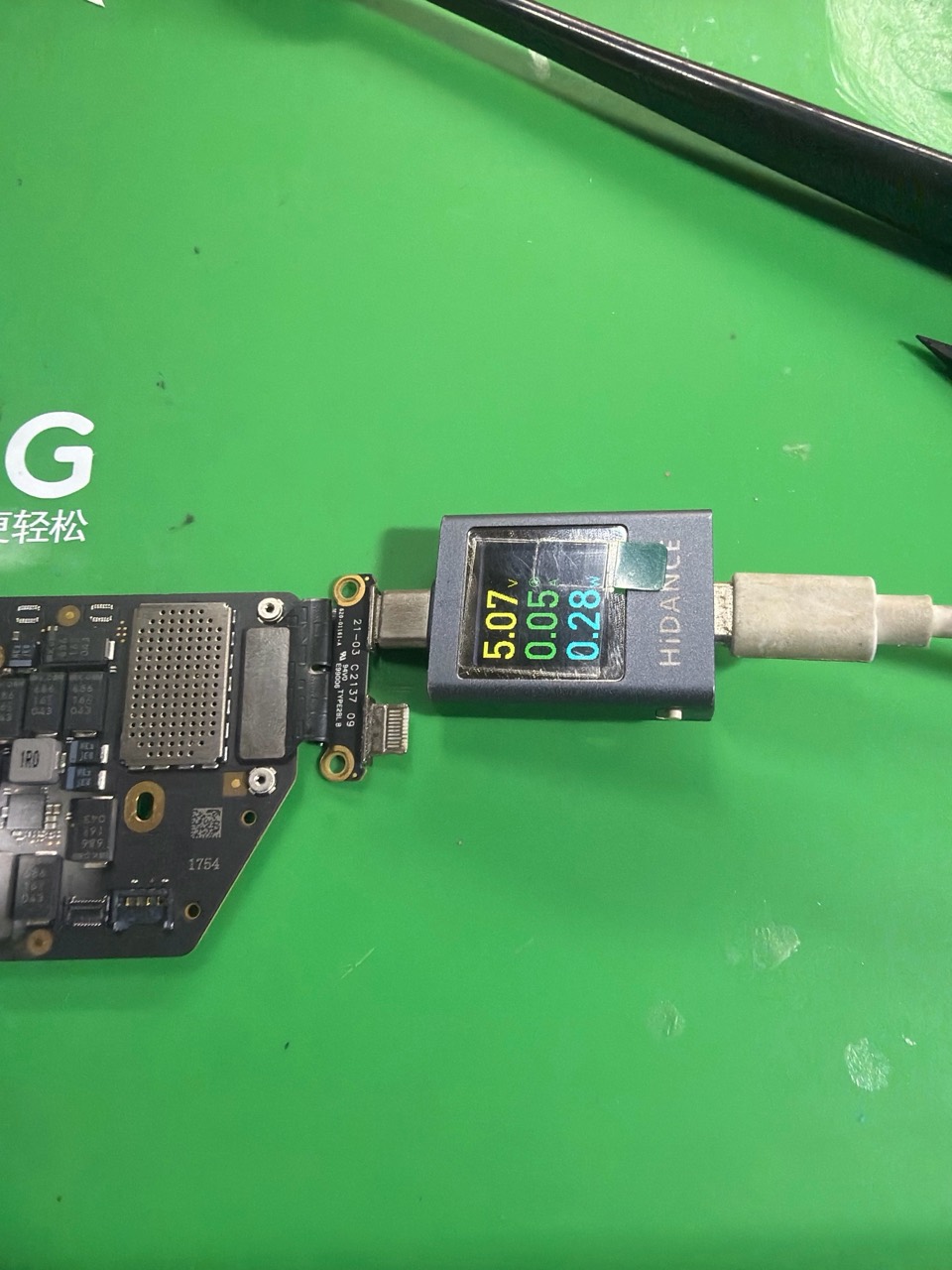 Meter USB-C menunjukkan sekitar 5.07V dan 0.05A pada papan MacBook Air M1 A2337