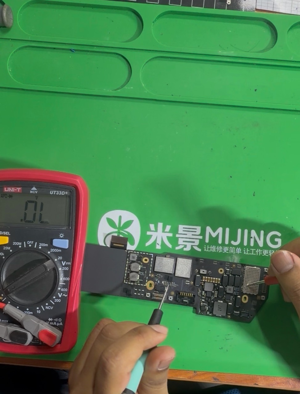 Juruteknik menggunakan multimeter untuk menyemak papan logik MacBook Air M1