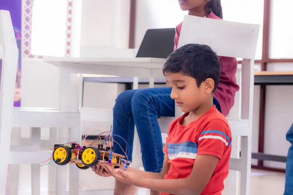 A child holding a finished line-following car, DreamSpace Academy Batticaloa, August 2025.