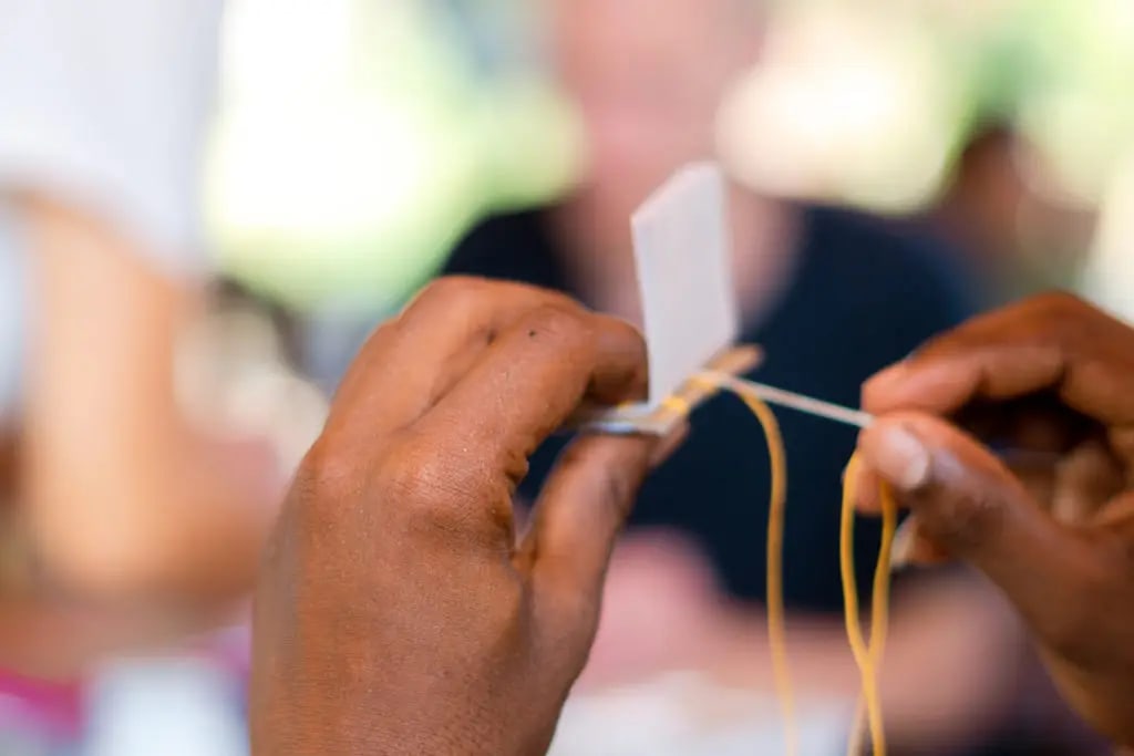 Sewing a coptic binding by hand, July 2022. Photo: Dinacon 2022.