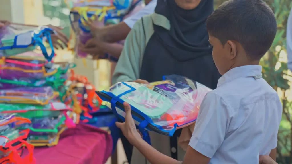A student receiving a pack of school supplies, Al Madeena Primary School, Polonnaruwa, December 2025.