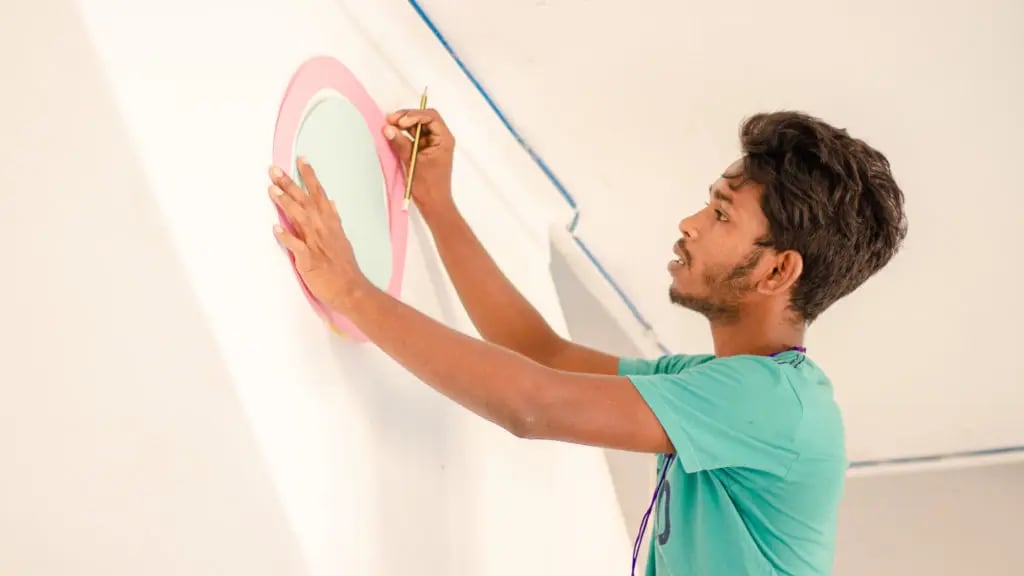 Drawing a circle on the wall with a handmade template. Photo: DreamSpace Story Lab.