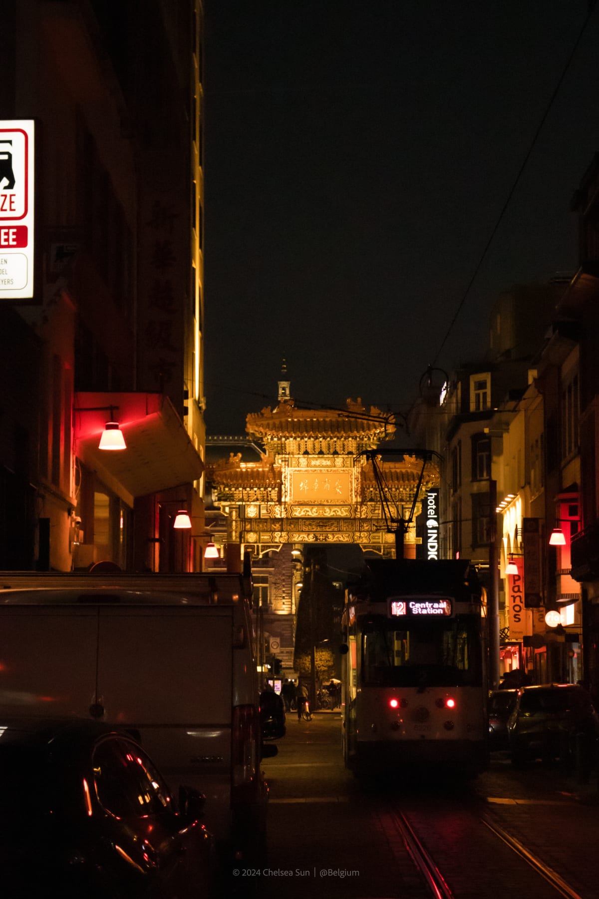 An illuminated ceremonial gate at the end of a narrow city street at night
